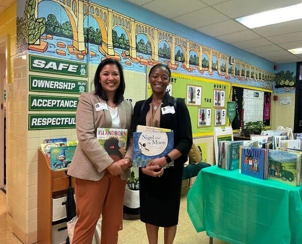 Two women stand with books